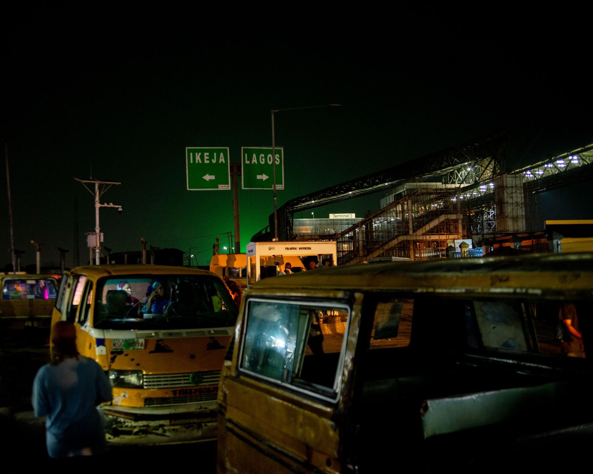 A Lagos road at night, lit by traffic and street signage.