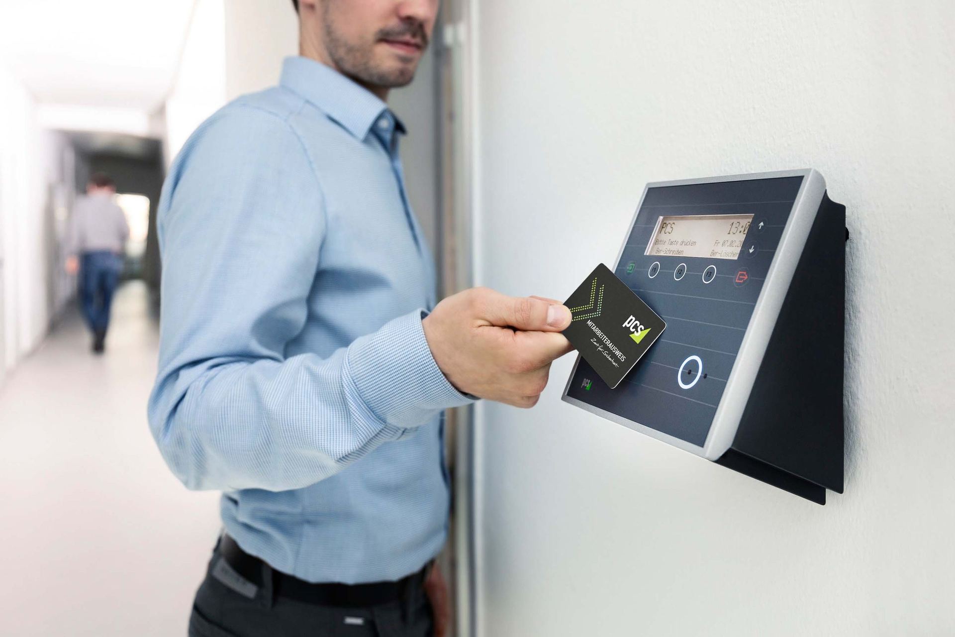 A staff member presenting a card to a wall-mounted access control reader.