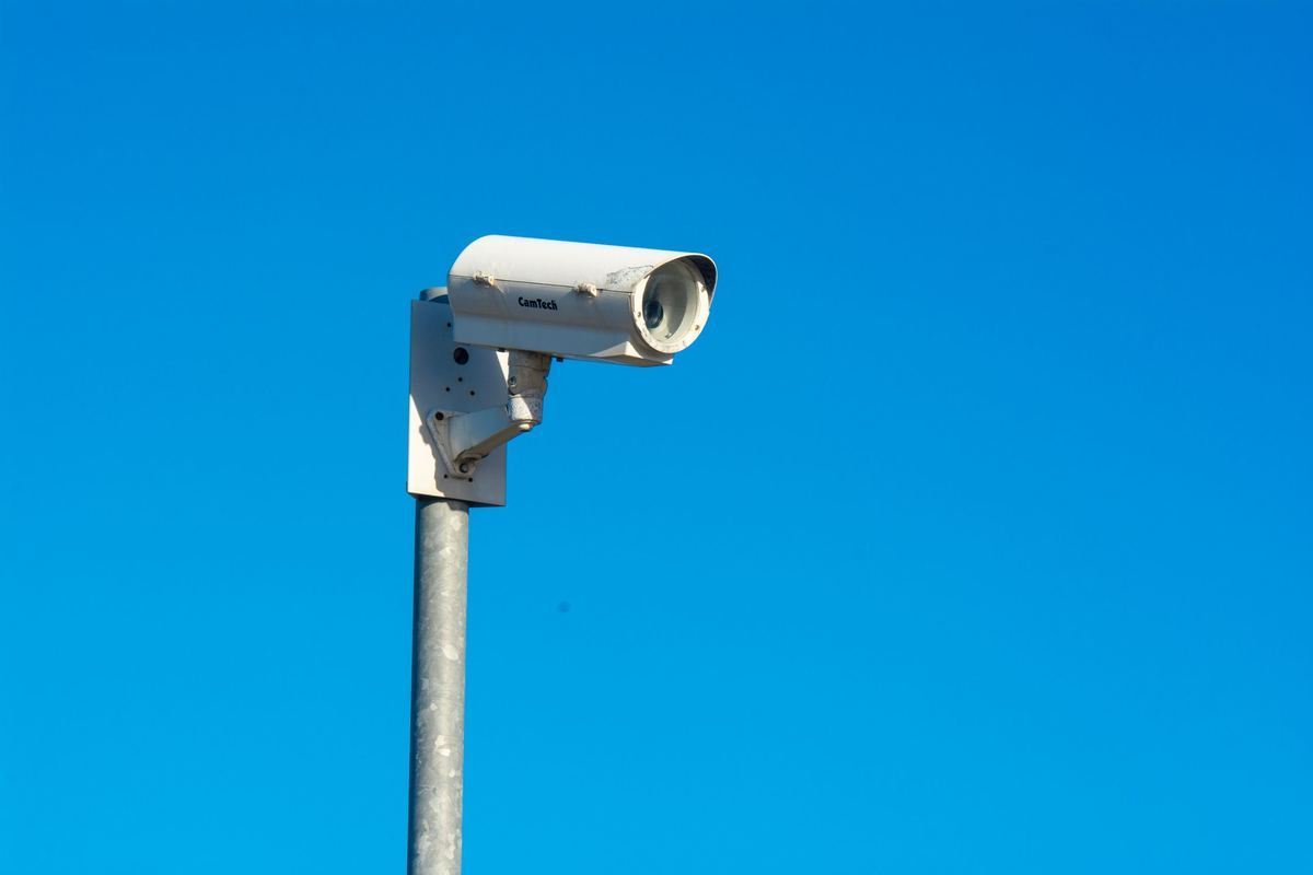 CCTV camera mounted against open sky.